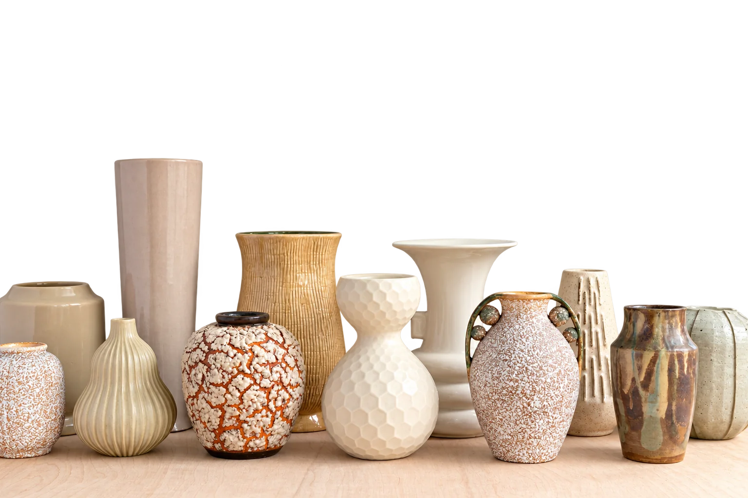 Une douzaine de vases en céramique de formes et de textures variées, dans des tons beige, crème et brun, alignés sur une surface en bois clair devant un mur blanc.